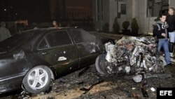 Fotografía cedida facilitada por la agencia siria de noticias SANA que muestra a unos policías sirios inspeccionando el lugar donde se ha registrado un atentado con coche bomba ante la sede del Ministerio del Interior sirio en Damasco, Siria. 