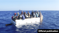 Diecisiete migrantes cubanos se sientan a bordo de un barco rústico aproximadamente a 54 millas al sur de Key West, Florida, el 18 de marzo de 2021. La tripulación del guardacostas Charles Sexton interceptó el barco rústico y repatrió a los 17 inmigrantes