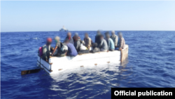 Diecisiete migrantes cubanos se sientan a bordo de un barco rústico aproximadamente 54 millas al sur de Key West, Florida, el 18 de marzo de 2021. La tripulación del guardacostas Charles Sexton interceptó el barco rústico y repatrió a los 17 inmigrantes.