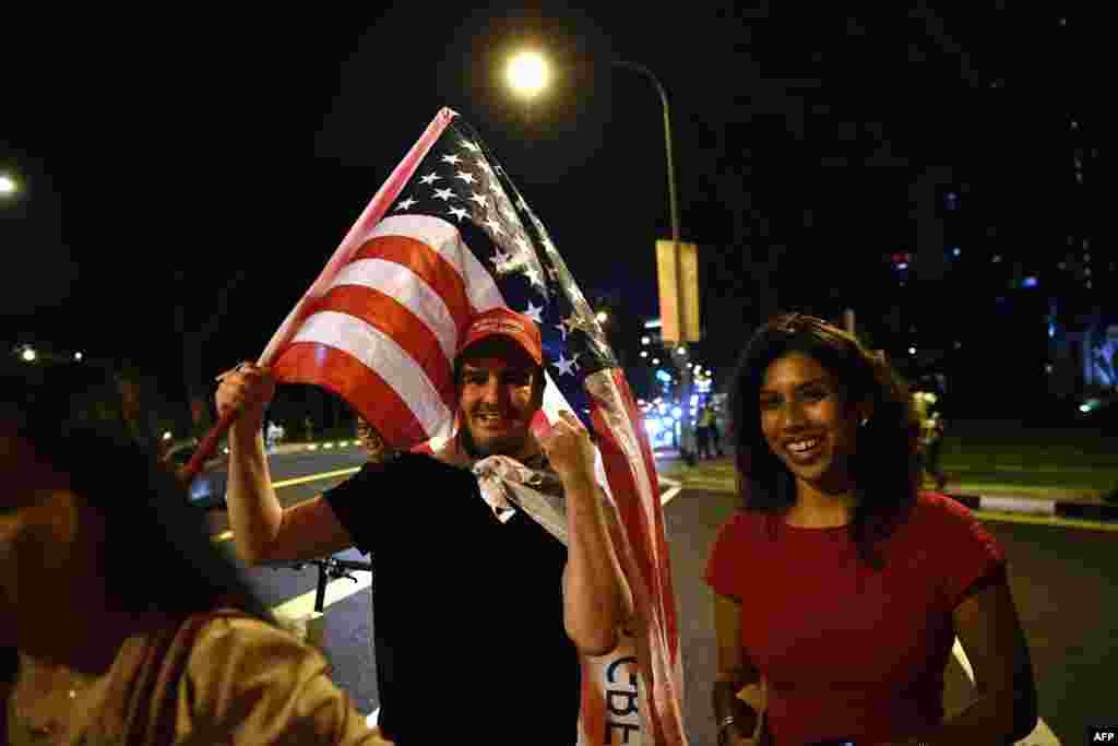 Con la bandera americana ante el paso de la caravana de Donald Trump en Singapur.