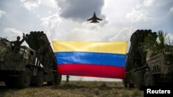 Un avión de combate Sukhoi Su-30MKV de la Fuerza Aérea de Venezuela, de fabricación rusa, ondea una bandera venezolana atada a lanzamisiles durante el ejercicio militar "Escudo Soberano 2015". (Archivo)