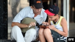 Dos personas navegan por la internet en un dispositivo móvi en una de las zonas habilitadas con Wifi en La Habana. 
