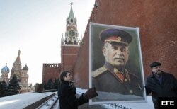 Un par de asistentes muestran un retrato del dictador soviético Iosif Stalin durante una ceremonia en recuerdo del 60º aniversario de la muerte del líder soviético en la plaza Roja de Moscú, Rusia.