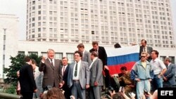 Foto de archivo, tomada el 19 de agosto de 1991, que muestra al presidente ruso, Boris Yeltsin (i), sobre un tanque aparcado frente a un edificio de la Federación Rusa, mientras sus seguidores sostienen una bandera de la Federación Rusa. 