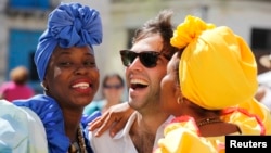 Modelos vestidas al estilo colonial besan a un turista en La Habana.