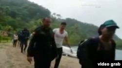 Policías colombianos conducen a un grupo de 16 cubanos que trataban de cruzar a pie la frontera con Panamá.