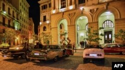 Autos antiguos en las afueras de un edificio de La Habana.