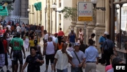 Varias personas caminan por una céntrica calle, junto a una Casa de Cambio, en La Habana (Cuba). 