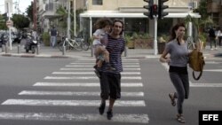 Una pareja israelí corre tras escuchar las sirenas de alarma en Tel Aviv, Israel