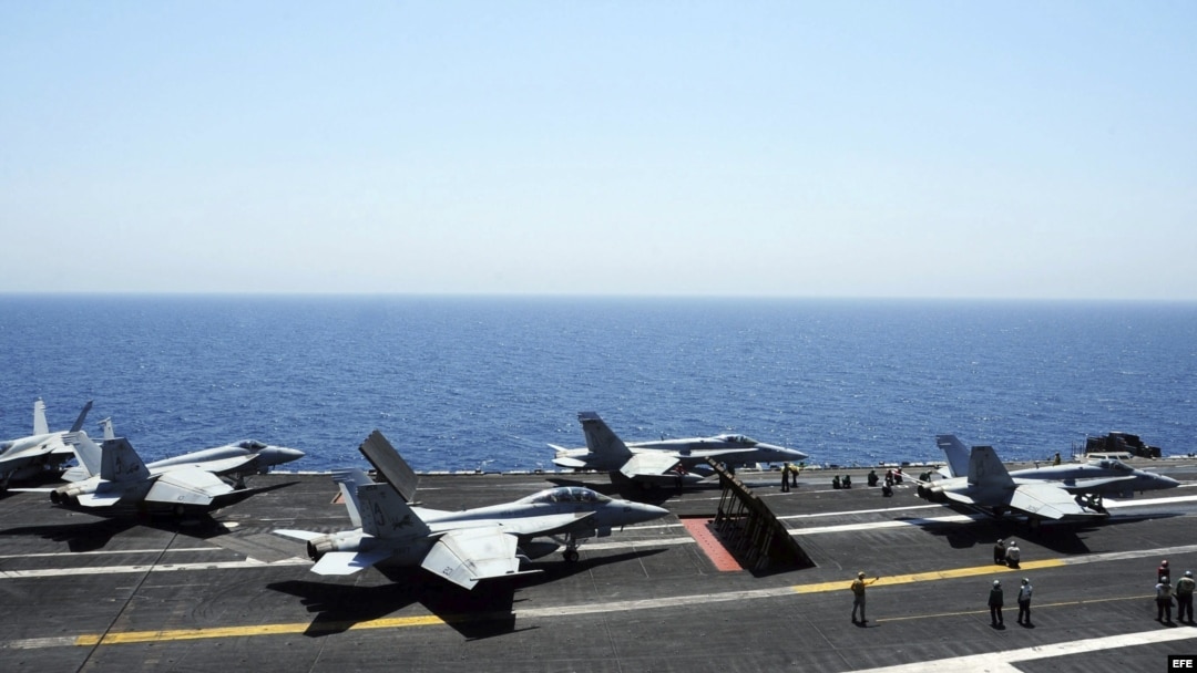Miembros de la Marina guiando a varios aviones Hornet F/A 18 para su despegue desde la cubierta de un portaaviones estadounidense.