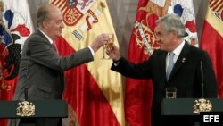 Aún convalece de 2 operaciones en la cadera, pero el rey (izq.) en la foto con el presidente chileno dijo estar “encantadísimo” del viaje.