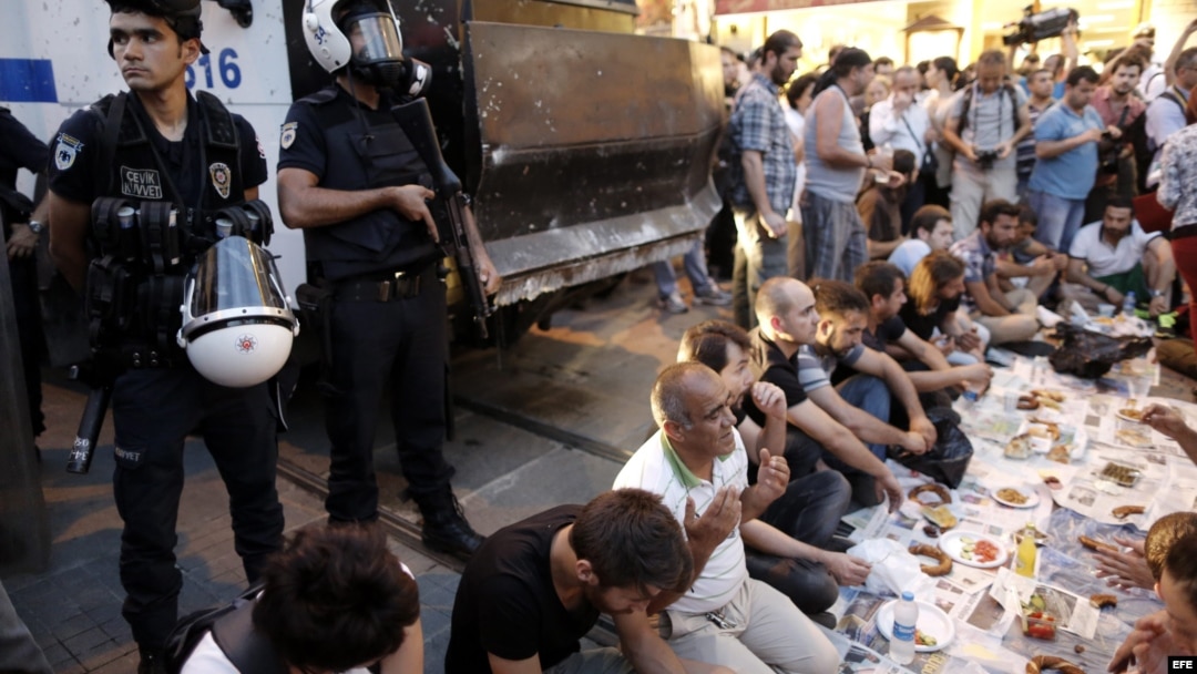 Manifestantes turcos comen en frente a policías antidisturbios,9 de julio de 2013, durante protesta antigobierno el primer día del Ramadan en Estambul (Turquía).