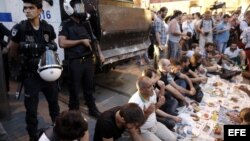 Manifestantes turcos comen en frente a policías antidisturbios,9 de julio de 2013, durante protesta antigobierno el primer día del Ramadan en Estambul (Turquía).