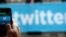 Un transeúnte toma fotografías al logo de la red social Twitter.