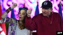 (FILES) This handout picture released by the official El 19 Digital news outlet shows Nicaraguan President Daniel Ortega and Co-President Rosario Murillo gesturing during Labor Day celebrations in Managua on 30 April, 2025.