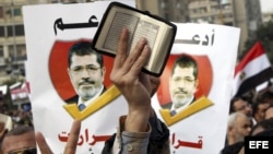 Un participante muestra una página del Corán mientras simpatizantes del presidente egipcio, Mohamed Mursi, corean consignas durante una manifestación convocada en el barrio de Nasr, en El Cairo, Egipto. 