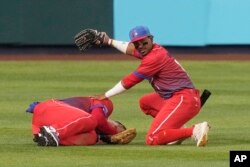 Roel Santos pide ayuda tras choque del tercera base Yoán Moncada contra su compañero en el sexto inning de la semifinal EEUU vs. Cuba, en el LoanDepot Park de Miami. (AP/Marta Lavandier)