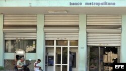Ciudadanos sacan dinero en los cajeros automáticos de un banco.