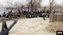 Militares afganos controlan a las personas que se han reunido frente a la base militar del distrito de Panjwai para protestar por el asesinato de 16 civiles afganos, el domingo, 11 de marzo de 2012.