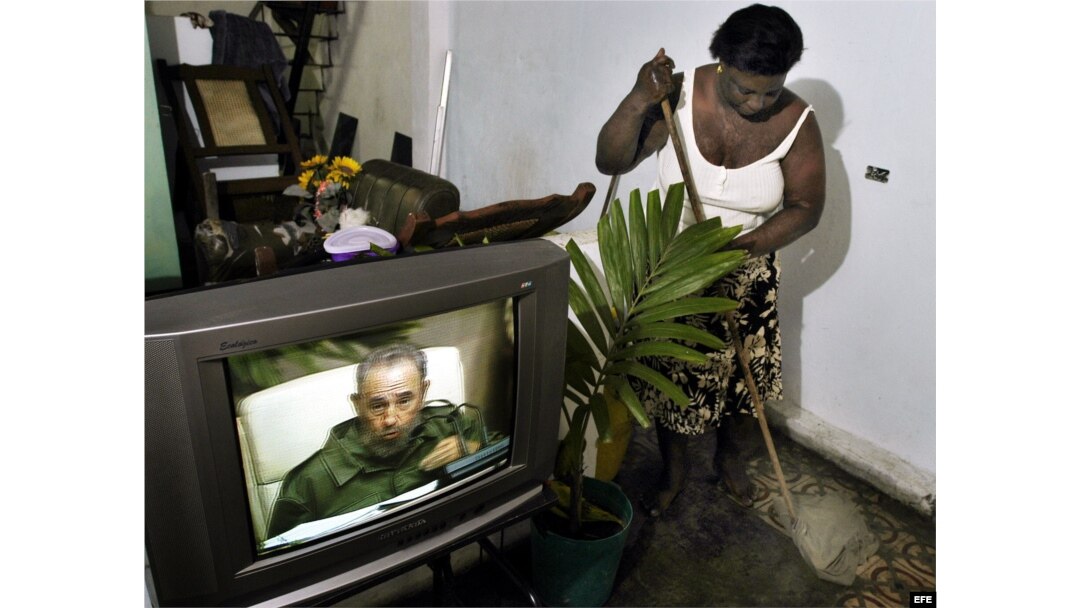 Archivo. Una mujer cubana limpia su casa mientras sigue por la TV la intervención especial de Fidel Castro.