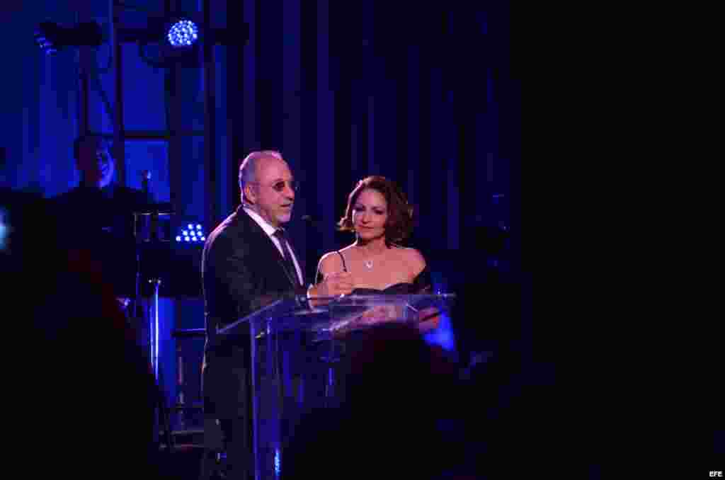 El productor y compositor Emilio Estefan le entrega una estatuilla a su esposa Gloria Estefan durante la ceremonia de los premios La Musa
