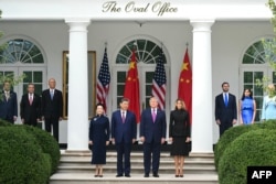 La primera dama de China, Peng Liyuan; el presidente de China, Xi Jinping; el presidente de Estados Unidos, Donald Trump; y la primera dama de Estados Unidos, Melania Trump, observan una revista militar en el Jardín de las Rosas de la Casa Blanca.