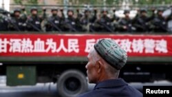 Un hombre uigur observa un camión que transporta policías paramilitares durante un mitin de juramento antiterrorista en Urumqi, Región Autónoma Uigur de Xinjiang, en 2014.