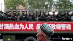 Un hombre uigur observa a policías paramilitares durante un mitin en Urumqi, China, en el 2014 (Reuters).