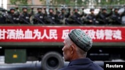 Un hombre uigur observa un camión que transporta policías paramilitares durante un mitin de juramento antiterrorista en Urumqi, Región Autónoma Uigur de Xinjiang, en 2014. (Reuters).