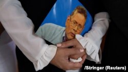 Claudia Vargas sostiene una foto de su esposo, el opositor nicaragüense Roberto Samcam, en su funeral en San José, Costa Rica, el 22 de junio de 2025.