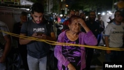 Varias personas permanecen en el lugar donde se derrumbó un edificio tras los dos sismos que sacudieron Caracas, Venezuela.
