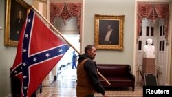 Un simpatizante del presidente Donald Trump porta una bandera confederada en el segundo piso del Capitolio, el 6 de enero de 2021. (Mike Theiler/Reuters).