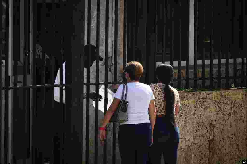 Dos personas esperan su turno en el exterior de la embajada de Estados Unidos el día después de la reapertura de los servicios consulares, en La Habana, Cuba, el 4 de mayo de 2022. (AP Foto/Ramón Espinosa)