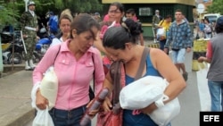 Dos mujeres venezolanos cargan alimentos comprados este sábado en Colombia