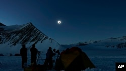 Varias personas observan un eclipse total de Sol desde el campamento Glaciar Unión, en la Antártida, el 4 de diciembre de 2021. (Felipe Trueba, Imagen Chile vía AP)