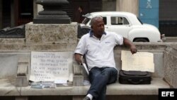Un hombre ofrece varias casas en venta sentado en un parque hoy, lunes 12 de noviembre de 2012, en La Habana (Cuba).