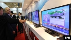 Varias personas observan una emisión de televisión digital en el stand de una compañía china que participa en la XV Convención y Feria Internacional Informática 2013.