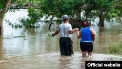 Una pareja se desplaza con el agua a la rodilla en una zona inundada en Cuba por la tormenta Alberto. (Vanguardia)
