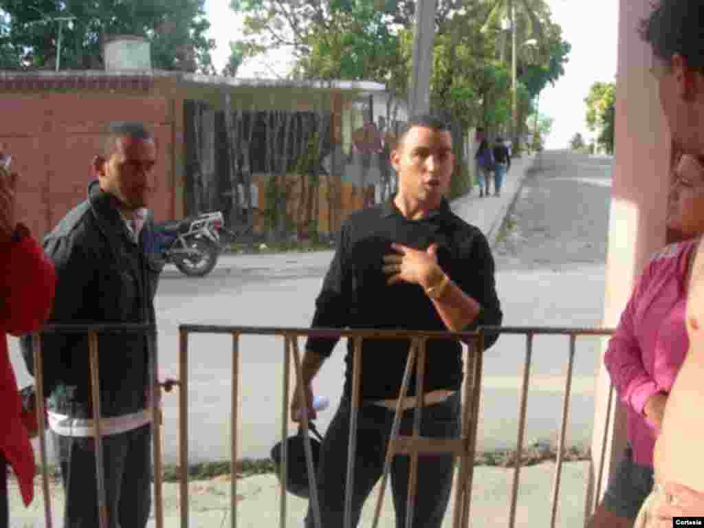Agentes policiales vestidos de civil advierte a Yadira Rodr&iacute;guez, (con blusa rosada), que no puede salir de su hogar durante la misa en La Habana.