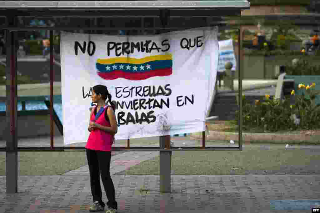 Una mujer permanece junto a un cartel durante protestas opositoras en la Plaza Altamira