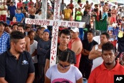 Migrantes de la caravana que caminan hacia Estados Unidos se reúnen en una cancha de baloncesto pública para pedir el paso legal a través de México, en Huixtla, estado de Chiapas, México, jueves 2 de noviembre de 2023. (AP Photo/Edgar Hernández Clemente)