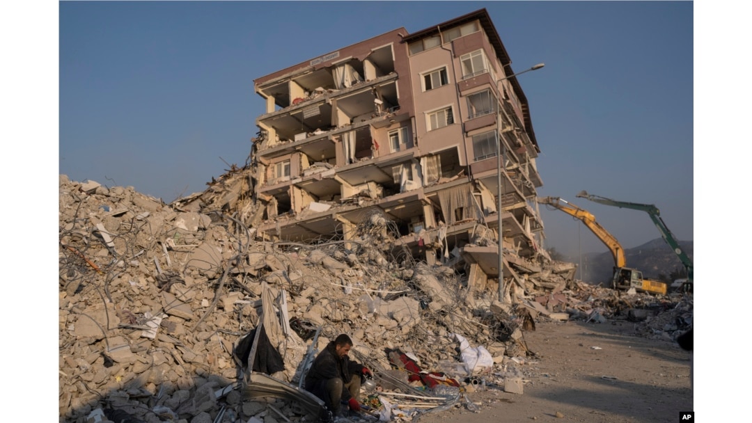 Un hombre se sienta en los escombros de un edificio derrumbado por los sismos recientes, el domingo 12 de febrero de 2023, en Antioquía, Turquía. (AP Foto/Petros Giannakouris)