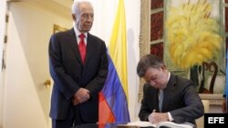 , Juan Manuel Santos (dcha), firma el libro de visitas junto a su homólogo israelí, Simon Peres (centro izda).