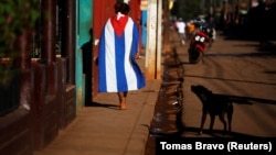 Un perro ladra a un transeúnte cubierto con la bandera cubana. (Reuters/Tomas Bravo/Archivo)