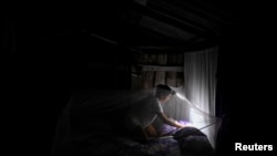 Deysys Fleitas, de 20 años, utiliza una linterna frontal durante un apagón mientras hace la cama y acomoda un mosquitero en su hogar, en Palpite, Ciénaga de Zapata, Cuba, el 7 de abril de 2026. REUTERS/Norlys Perez