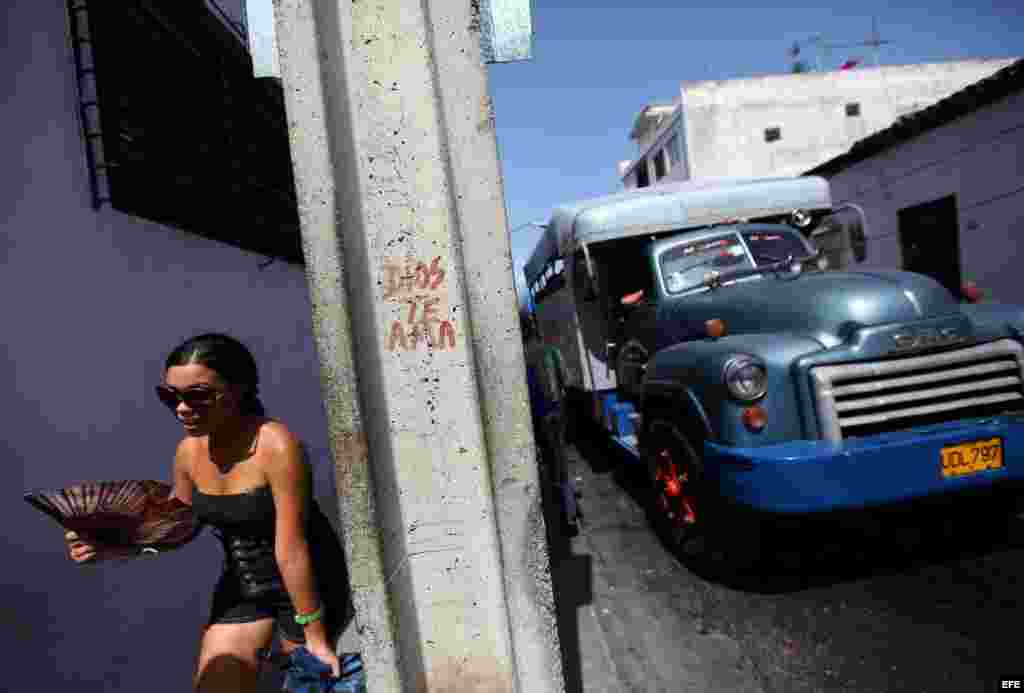 Una joven camina cerca de un camión de transporte de pasajeros en la ciudad de Santiago de Cuba.