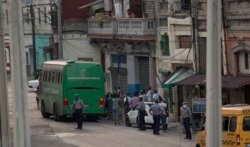 Sospechosos de coronavirus son evacuados en un bus del MINSAP y escoltados por la policía cerca del Mercado de Cuatro Caminos, en La Habana. (AP/Ismael Francisco)