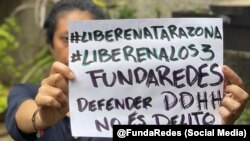 Una mujer con un cartel exige la liberación de los 3 miembros de la ONG FundaRedes