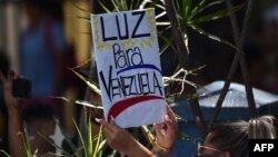 Una mujer pide en un cartel "Luz para Venezuela" durante una marcha de la oposición este 27 de marzo. 