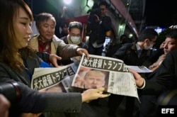 Una empleada de un periódico ofrece a unos viandantes ejemplares de una edición extraordinaria, en la que se informa sobre la victoria del candidato republicano a la presidencia estadounidense, Donald Trump, en Tokio (Japón) hoy, 9 de noviembre de 2016.